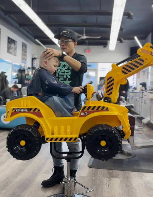 Child getting a haircut in the excavator chair at The Barbershop FSJ, Fort St John